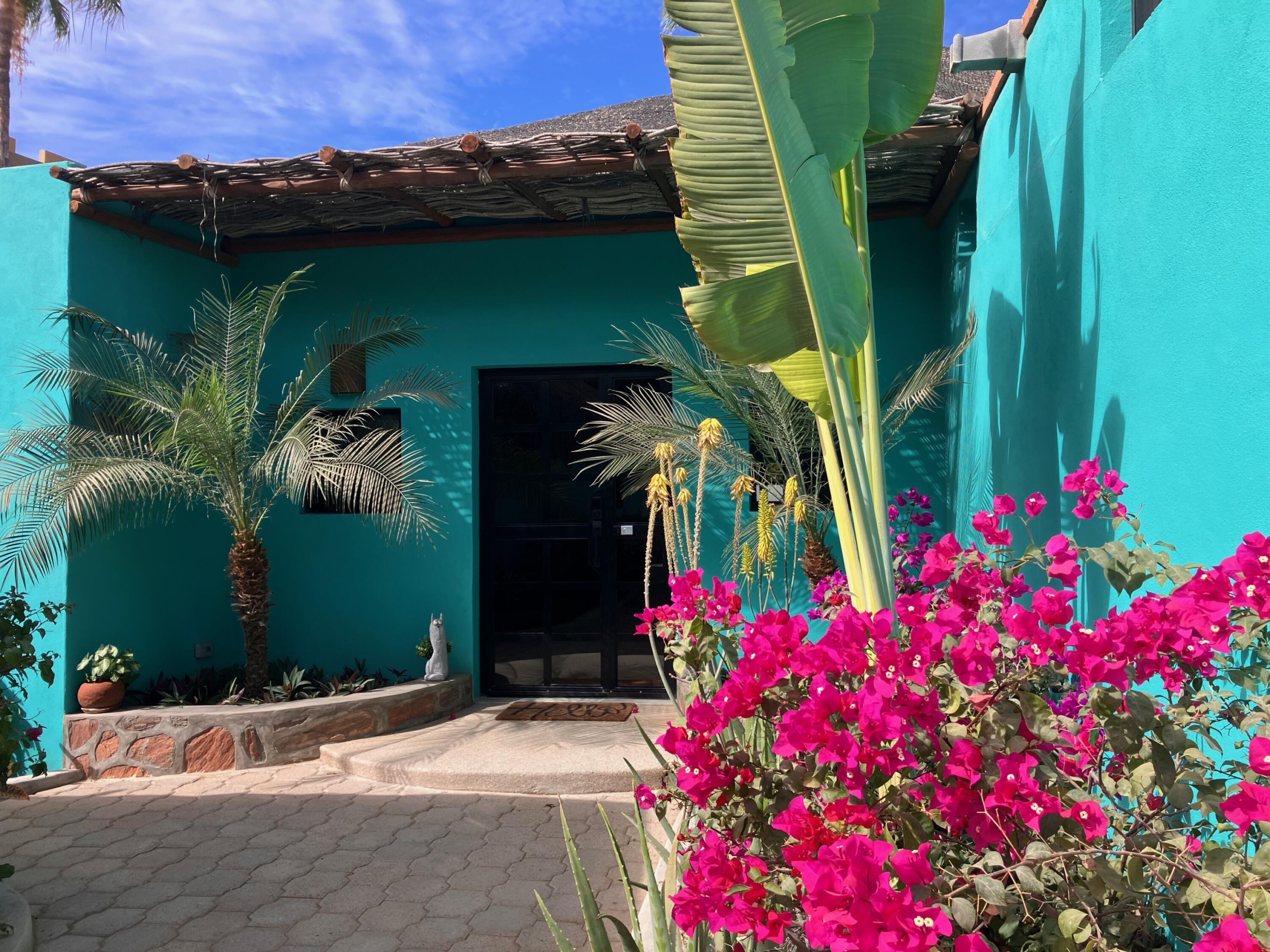 Pedregal Pescadero Casa Flora, A Private Garden Oasis, Step into Casa Flora, a serene retreat set within a lush, private garden oasis. The main residence, complete with a spacious covered porch, is beautifully nestled among mature palm trees, vibrant flowering plants, and rich tropical foliage, creating a peaceful and inviting atmosphere.All three bedrooms offer tranquil – 9 Mutualismo, Pacific, BS