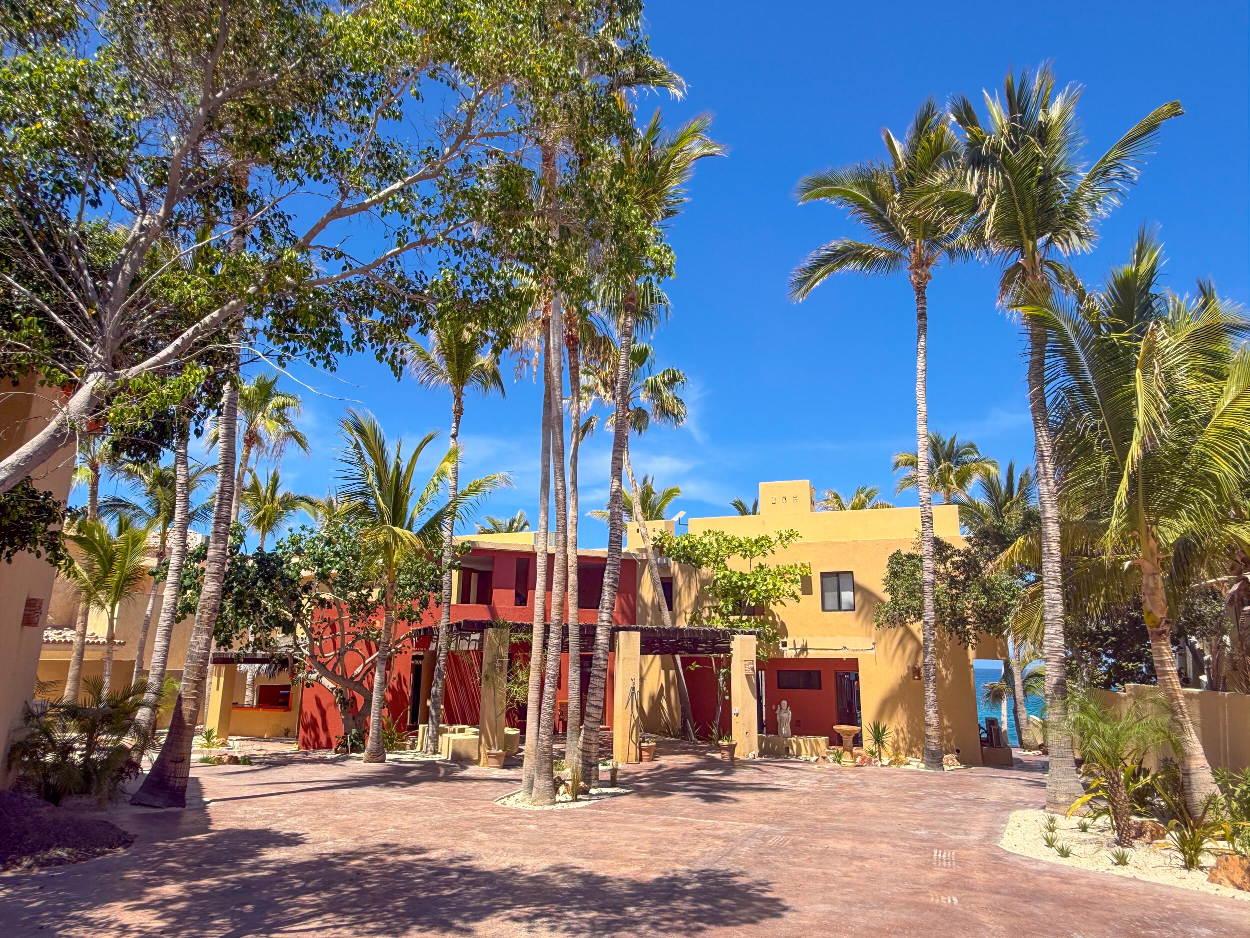 Pedregal Pescadero Casa Flora, A Private Garden Oasis, Step into Casa Flora, a serene retreat set within a lush, private garden oasis. The main residence, complete with a spacious covered porch, is beautifully nestled among mature palm trees, vibrant flowering plants, and rich tropical foliage, creating a peaceful and inviting atmosphere.All three bedrooms offer tranquil – Casa Laura, East Cape, East Cape, BS